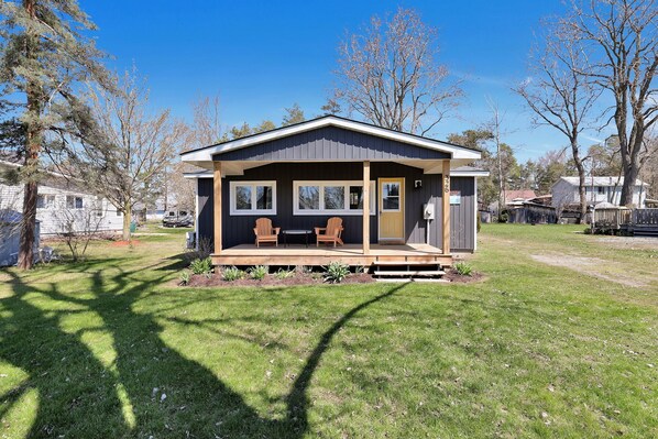 A single-story house with a porch, two windows, and a door. - Cozy Beach Cottage with Sauna & Spacious Backyard just 5mins from the Beach (Port Rowan)