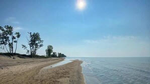 A beach with a clear sky and the sun shining. - Cozy Beach Cottage with Sauna & Spacious Backyard just 5mins from the Beach (Port Rowan)