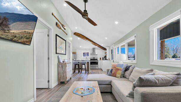 A spacious living area with a large sofa, a coffee table, and a kitchen in the background. - Cozy Beach Cottage with Sauna & Spacious Backyard just 5mins from the Beach (Port Rowan)