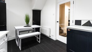 A modern kitchen with a white countertop, black cabinets, and a white bench. - STUNNING 5 BEDROOM TOWNHOUSE 5 MINS TO CITY CENTRE (Lisburn)