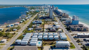 An aerial view of a coastal town with a marina, residential buildings, and a tall hotel.