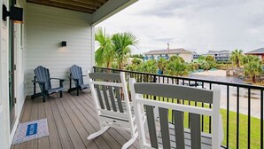 Una terraza de madera con dos sillas Adirondack, una mesita y un felpudo.