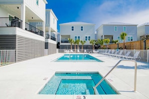 Un espace piscine comprenant deux piscines, une clôture blanche et un bâtiment doté de balcons.