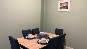 Un comedor con una mesa de madera y sillas negras, un cuenco decorativo azul y platos blancos.
