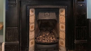 Una chimenea con un espejo encima, un jarrón en la repisa y un candelabro a cada lado.