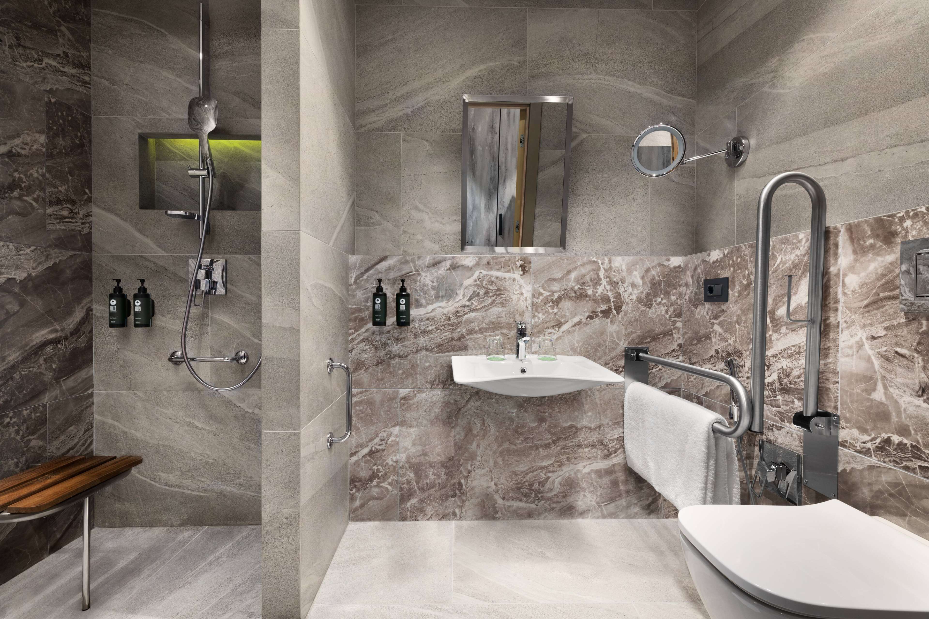 A modern bathroom with a shower, sink, and toilet.