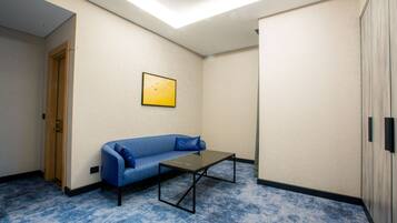 A room with a blue patterned sofa, a small table, and a door.
