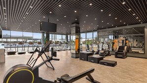 A modern gym with cardio machines, weight benches, and a large mirror wall.