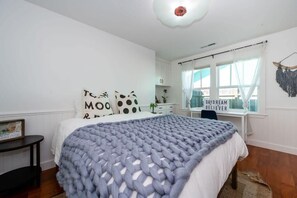 Un dormitorio con una cama, una mesita de noche, una ventana con cortinas y un muro decorado.