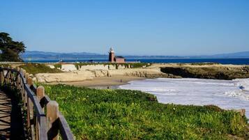 A coastal scene with a lighthouse, a wooden walkway, and a rocky shoreline.