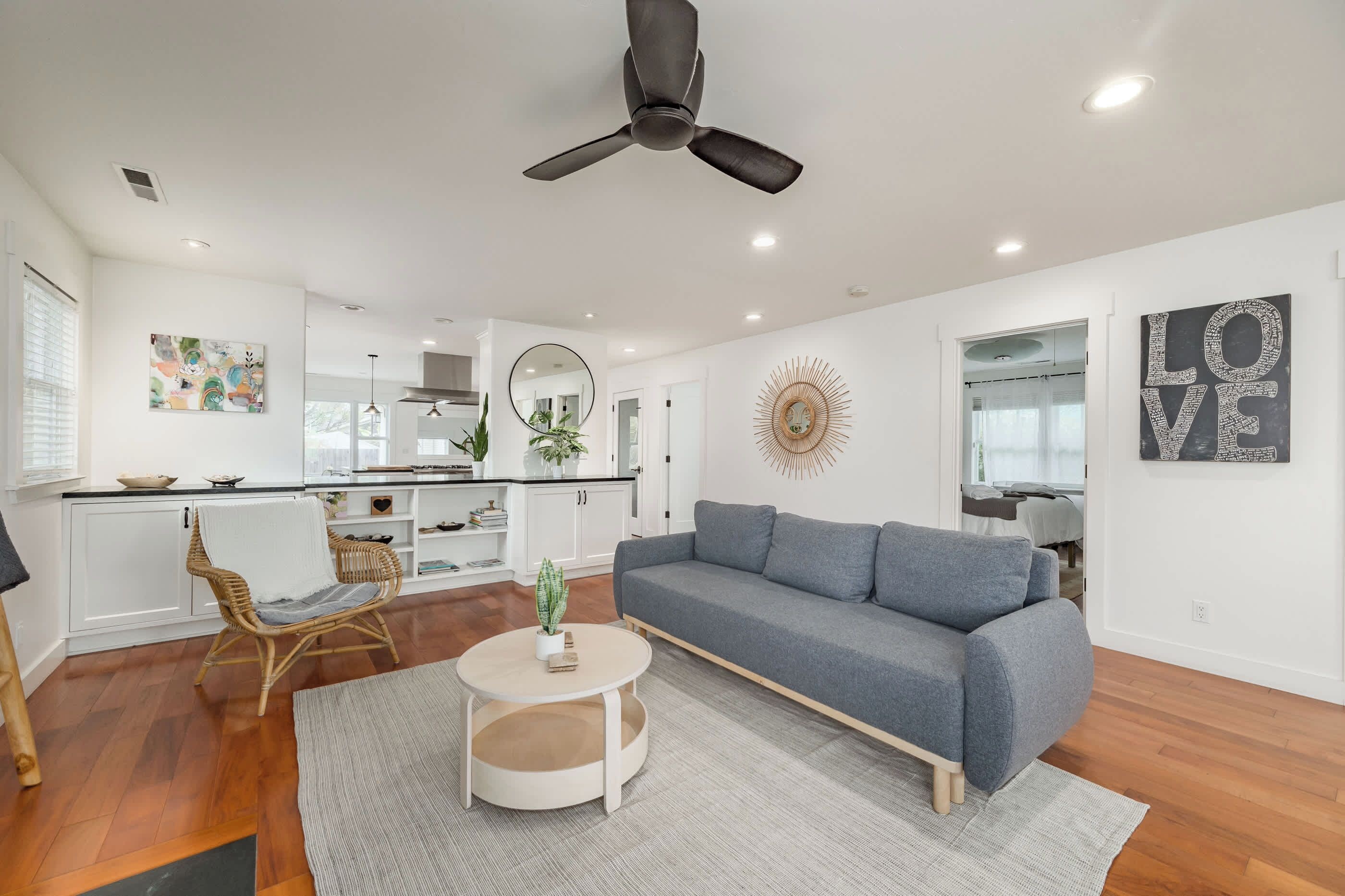 A modern living room with a grey sofa, a round coffee table, and a ceiling fan.