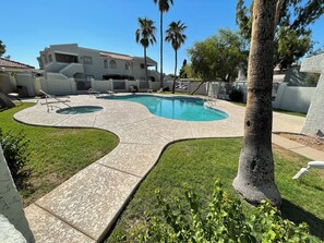 A swimming pool with a wavy edge, surrounded by a grassy area and palm trees. - Cozy Home/ASU/Spring Training/Restaurants & More (Tempe)