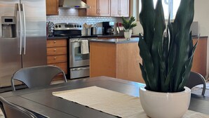A modern kitchen with stainless steel appliances, wooden cabinets, and a large potted plant on the island. - Cubs Stadium in backyard/Heated Pool /Dog Friendly (Mesa)