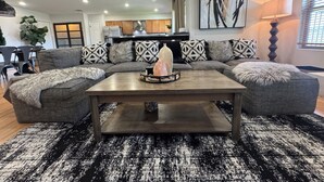 A modern living room with a sectional sofa, a coffee table, and a large abstract painting.