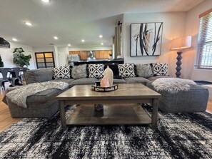 Ein modernes Wohnzimmer mit einem Ecksofa, einem Couchtisch und einem großen abstrakten Gemälde.