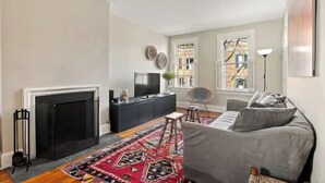 A living room with a fireplace, a sofa, a TV, and a patterned rug. - NO NEED TO LOOK ANY FURTHER! (Washington)