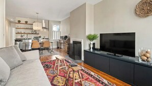 A modern living room with a sofa, a TV, and a kitchen in the background. - NO NEED TO LOOK ANY FURTHER! (Washington)