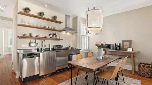 A modern kitchen with stainless steel appliances, wooden shelves, and a dining area with a wooden table and chairs. - NO NEED TO LOOK ANY FURTHER! (Washington)