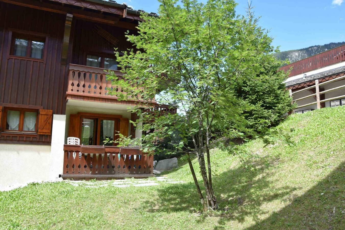 Una baita di legno con un balcone, immersa nel verde e su una collina.