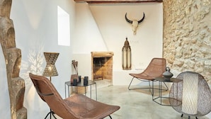 A rustic interior with a stone wall, a fireplace, and two wicker chairs. - LOOK NO FURTHER! Gorgeous old finca with sea view! (Sant Joan de Jabritja)