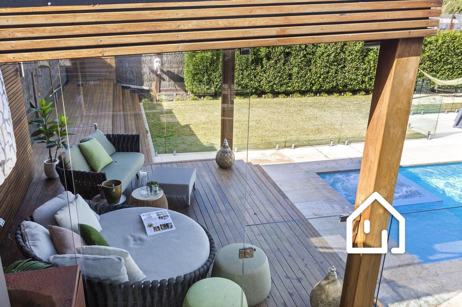 A wooden deck with outdoor seating, a pool, and a view of the backyard.