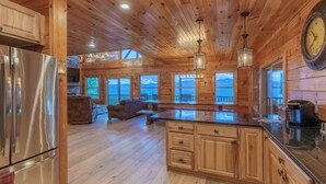 Cocina rústica y espaciosa en una cabaña de troncos, con alacenas de madera, refrigerador de acero inoxidable y una isla grande con pileta.