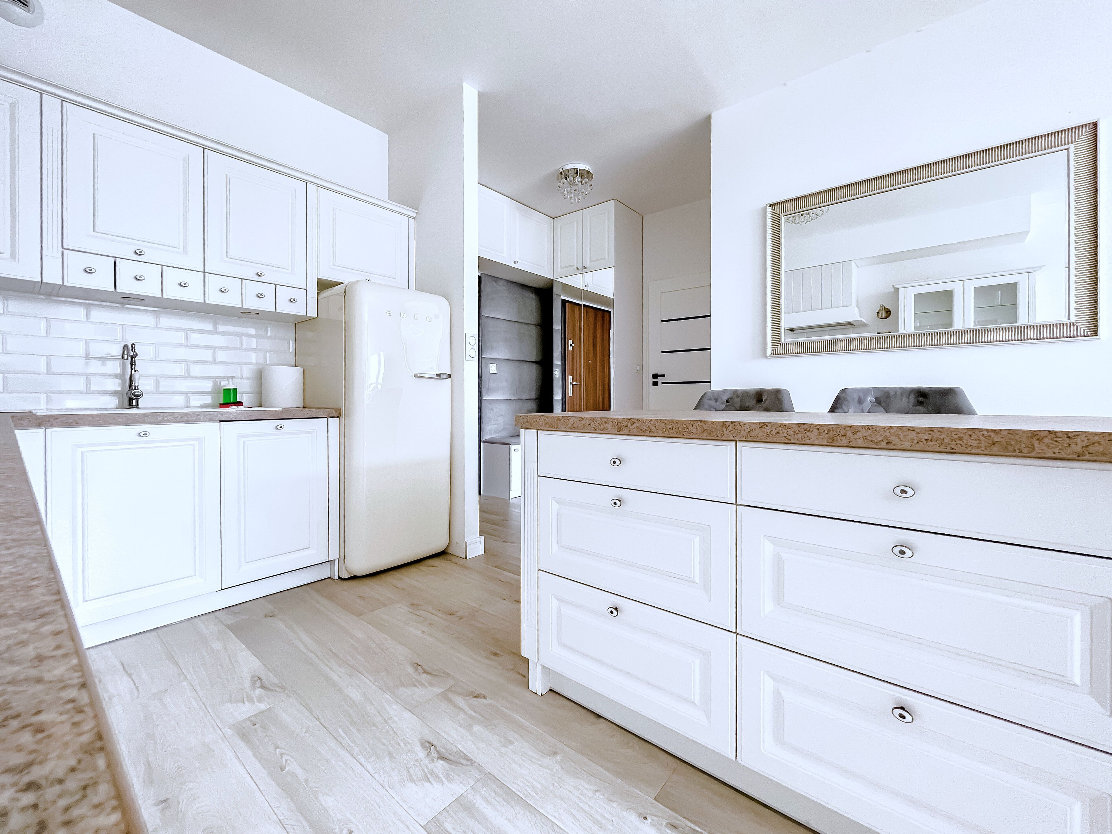 A modern kitchen with white cabinetry, a granite countertop, and a built-in refrigerator.