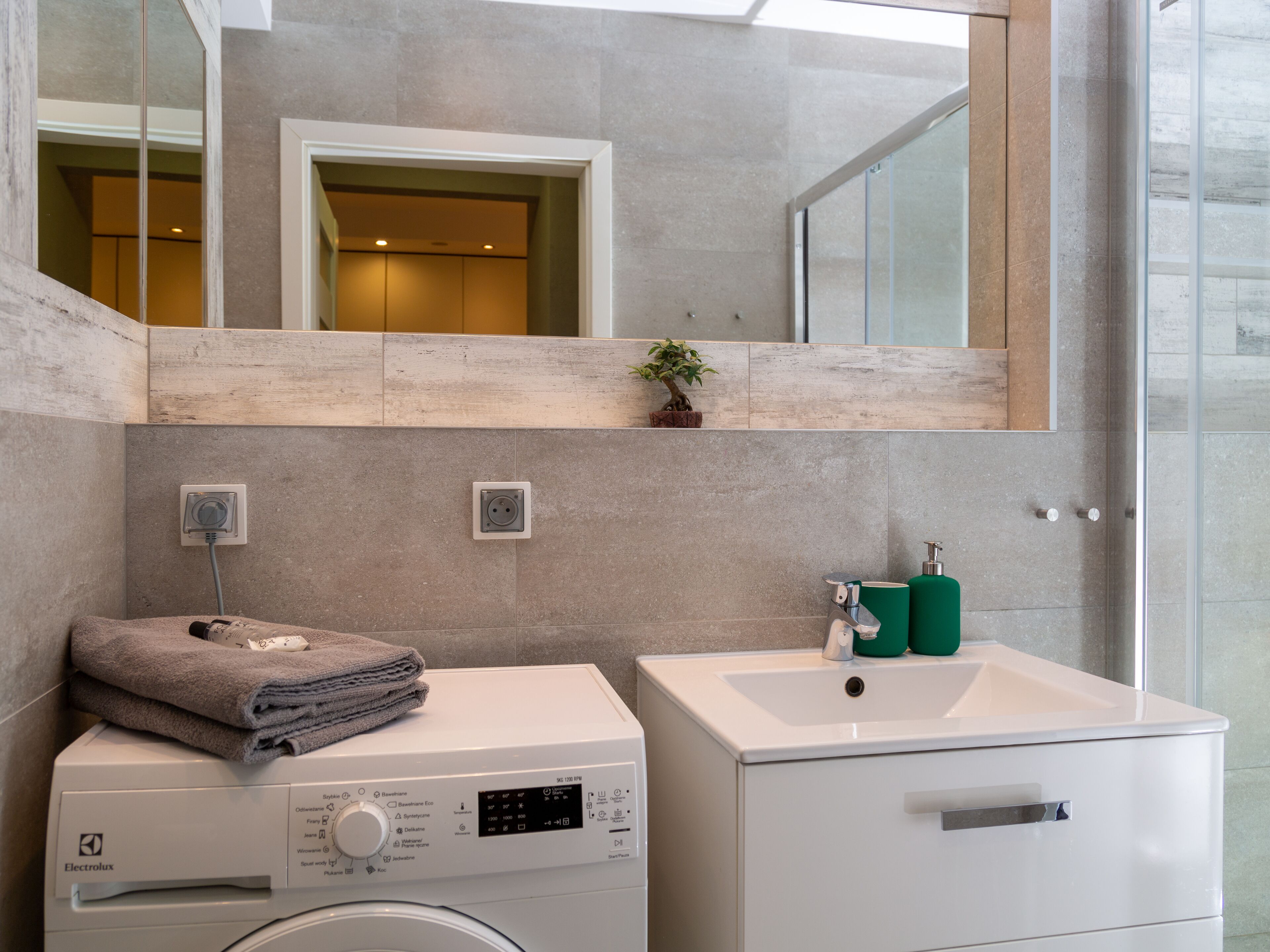 Ein modernes Badezimmer mit Waschmaschine, Waschbecken und Spiegel.