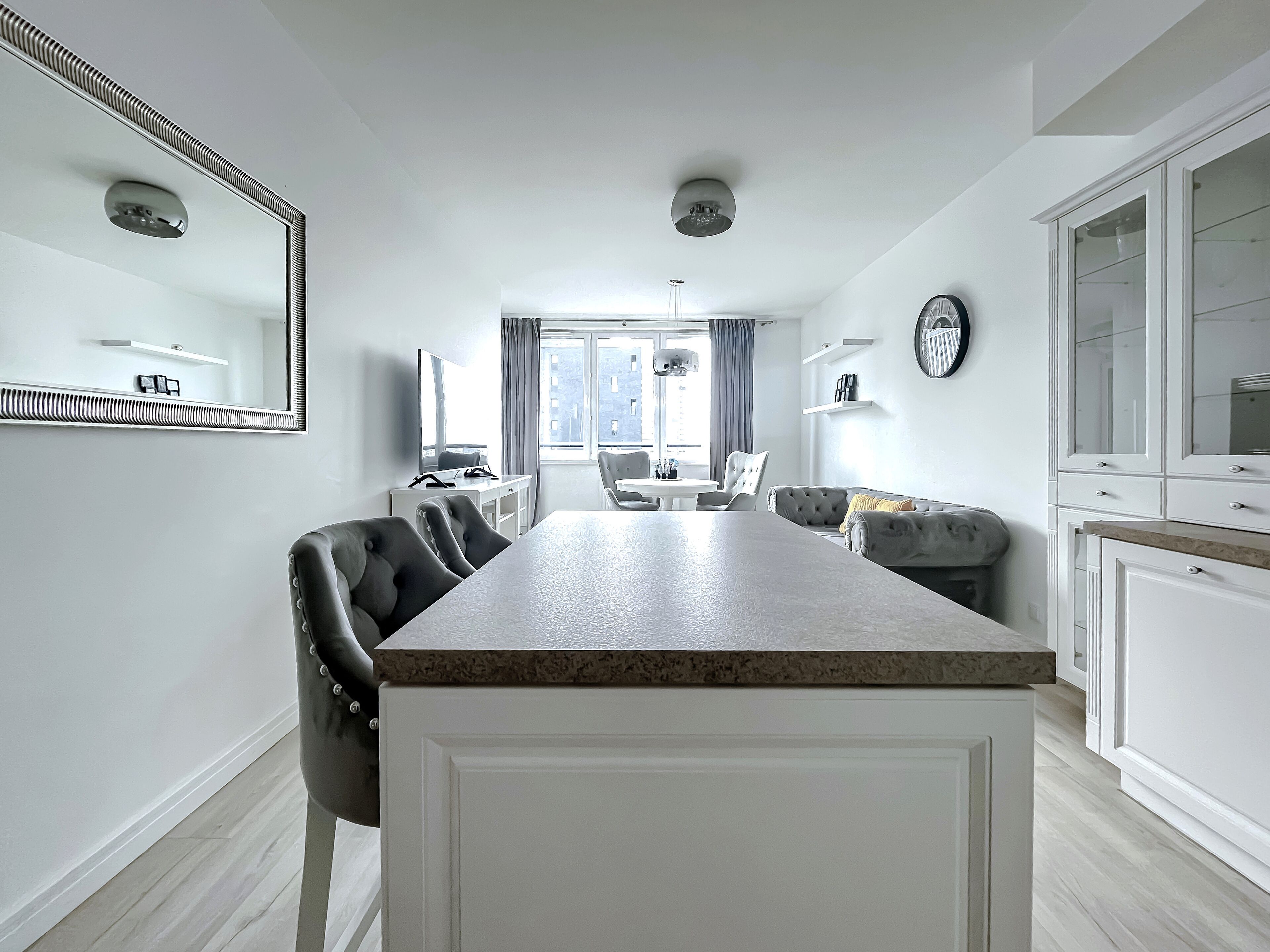 Une chambre d’hôtel moderne dotée d’un coin repas, d’un grand miroir, d’un canapé et d’un coin cuisine.