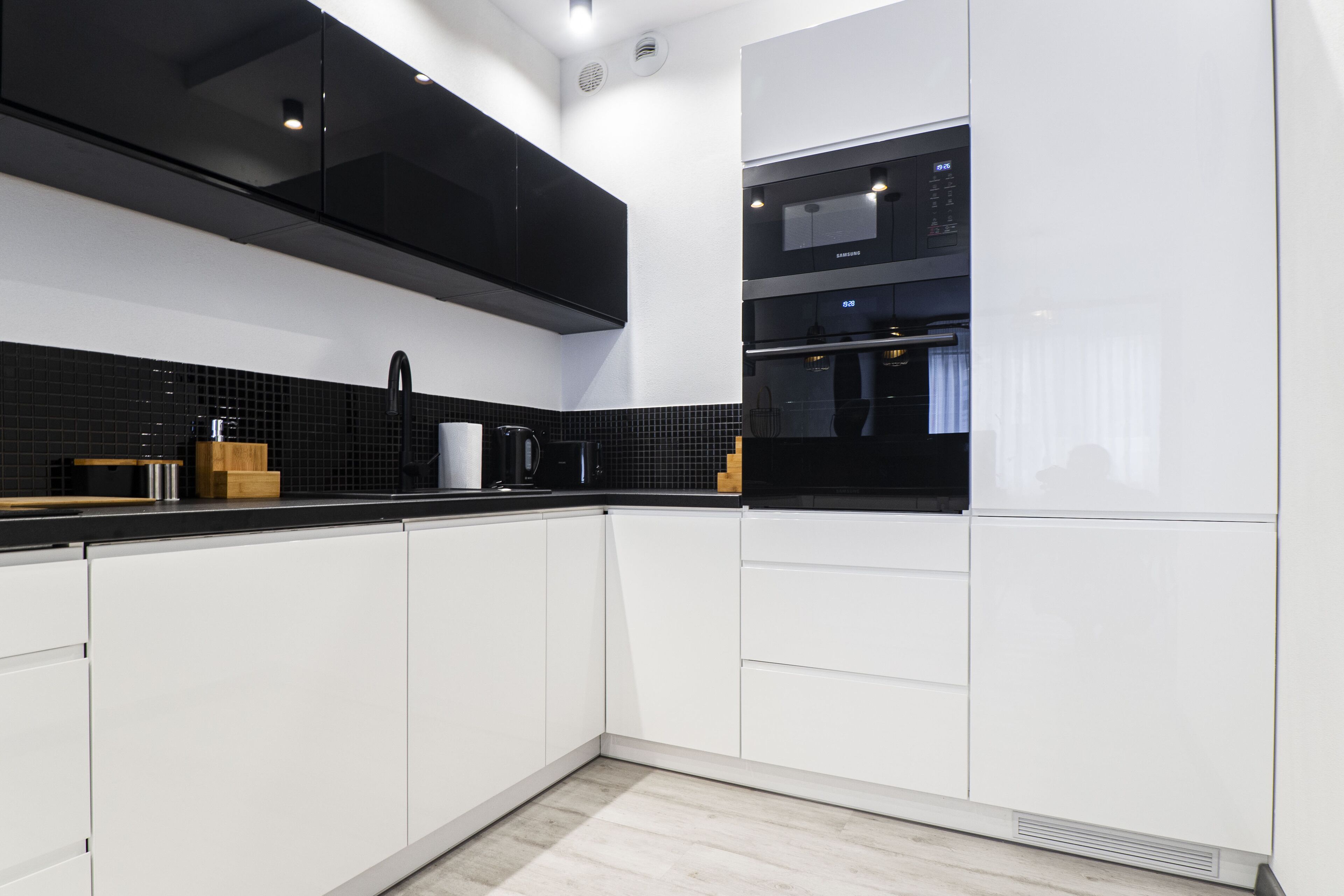 A modern kitchen with white cabinets, black countertops, and a built-in oven.