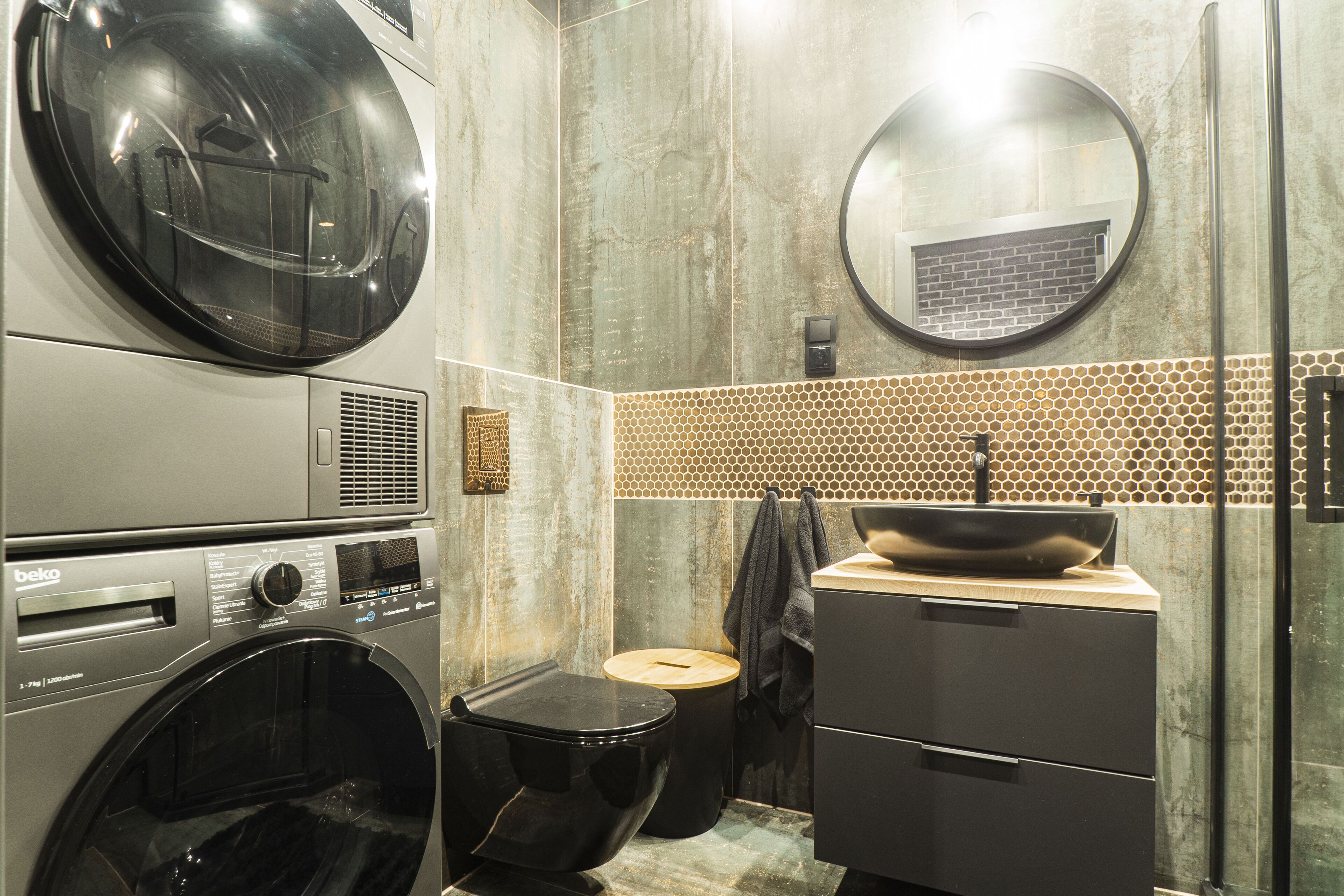 Un baño moderno con lavadora, inodoro, lavamanos con lavabo y un espejo grande.