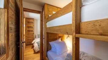 Una camera con un letto a castello in legno e una porta che dà su un'altra stanza.