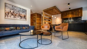 Ein modernes Wohnzimmer mit einer Couch, zwei Ledersesseln, einem Couchtisch und einem Kamin.