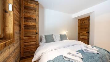 A bedroom with a wooden wardrobe, a bed with white bedding, and a blue throw blanket.