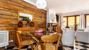 A dining area with a glass table, wooden chairs, a white ceiling light, and a checkered floor. - Cas Pedri (Can Picafort)