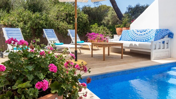 A poolside area with lounge chairs, a table, and a covered seating area. - Cas Pedri (Can Picafort)