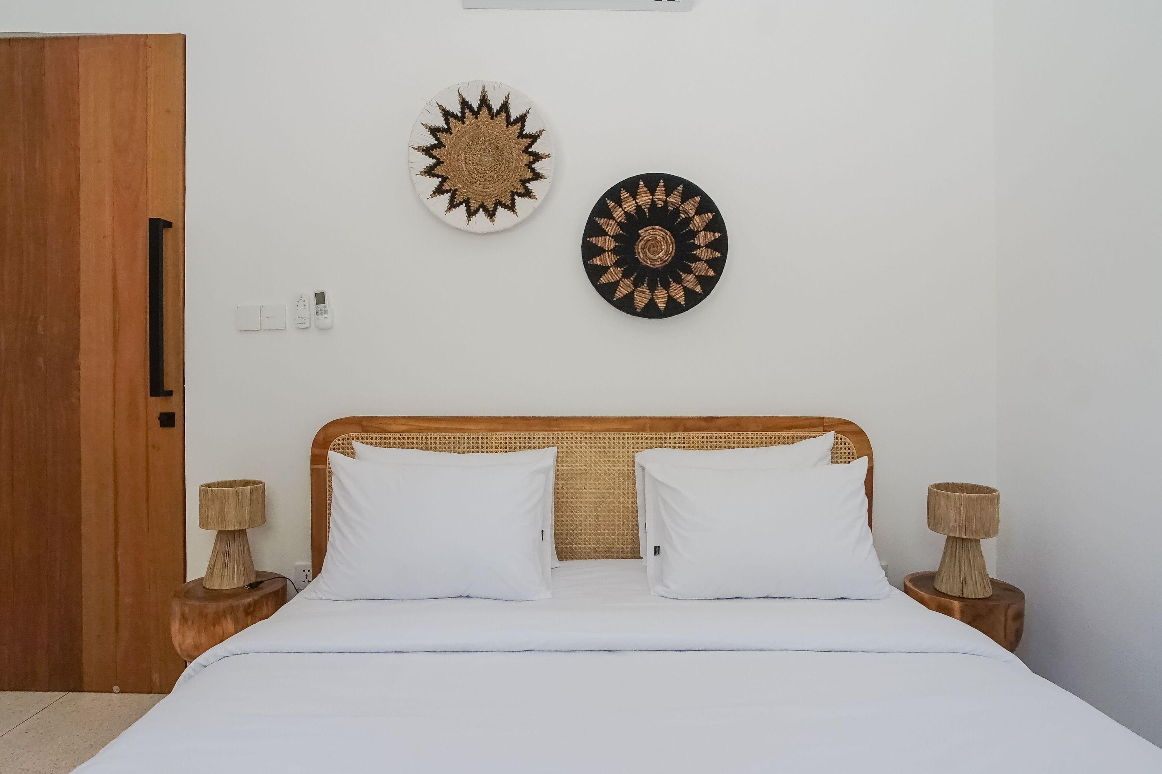 A neatly made bed with white linens, two bedside lamps, and two wall-mounted decorative plates.