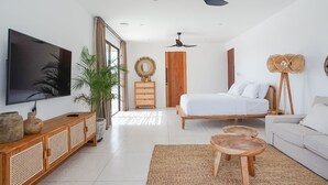 A modern bedroom with a bed, a TV, a ceiling fan, and a large window. - Avanoa Villa (Canggu)