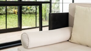 A modern room with a large window, a beige sofa, and a black headboard. - The Dan-els By Zuzu (Nusa Dua)