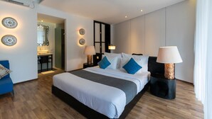 A modern hotel room with a large bed, bedside tables, and a desk with a chair. - The Dan-els By Zuzu (Nusa Dua)