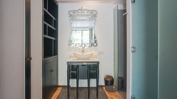 A bathroom with a white sink, a mirror with an ornate frame, and a wooden floor. - Swarnadwipa Villa (Nusa Dua)