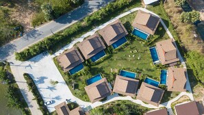 Vista aérea de un área residencial con varias casas, cada una con piscina propia y rodeada de vegetación.