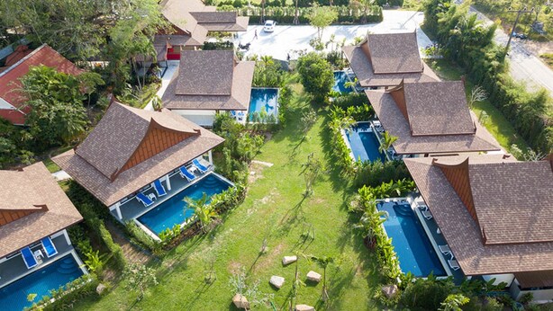 Un barrio residencial con varias casas, cada una con piscina y césped cuidado.