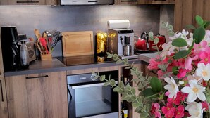 Une cuisine moderne avec des meubles en bois, un four encastré et un coin repas comprenant une table et des chaises.