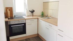 A kitchen with a stove, oven, sink, and cabinets. - Vacation apartment in Cottbus-Klein Ströbitz near the bathing lake (Cottbus)