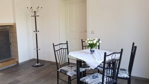 A dining area with a round table covered by a white tablecloth, surrounded by four chairs with patterned cushions. A tall, black floor lamp stands beside the table. - Vacation apartment in Cottbus-Klein Ströbitz near the bathing lake (Cottbus)