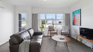 A modern living room with a leather sofa, a round coffee table, and a television on a wooden stand.