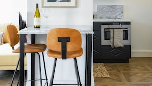 Een moderne keuken met een marmeren aanrecht, een zwart-wit fornuis en een ingelijste foto aan de muur.