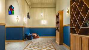 Een gang met blauw-witte wanden, een houten kast, een glas-in-loodraam en een patroon vloer.