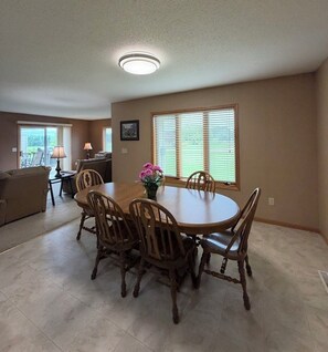 A dining area with a round table, wooden chairs, and a vase of flowers.